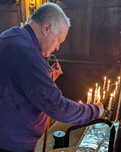Image shows the Bishop of Truro lighting a candle. There are a number of candles already lit