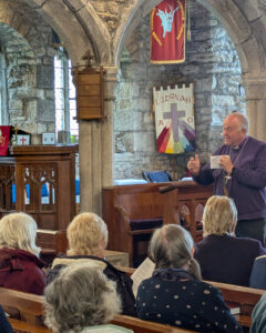 The image shows the bishop in a church with a congregation.