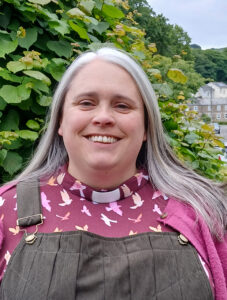 Image shows Revd Grace Kanungha stood outside with shrubbery behind her.