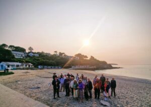 Image shows the bishop on the beach at sunrise with fellow walkers.
