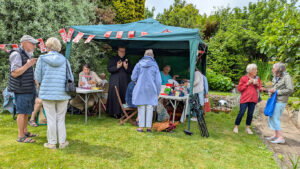 People stood on a lawn looking at a stall with Christian Aid flags.