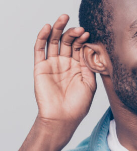Image shows a person smiling at the camera with their hand to their ear to signify listening. iStock image: Deagreez