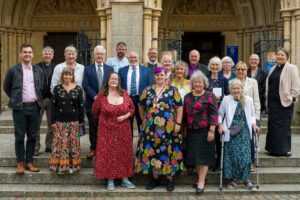 Group of people on the steps of Truro Cathedral looking at the camera.