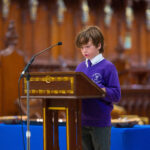 A child in purple reading from the pulpit in the cathedral.