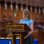 A child in blue reading from the pulpit in the cathedral.