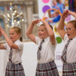 Three children dancing and singing.