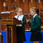Two children in green reading from the pulpit in the cathedral.