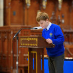 A child in blue reading from the pulpit in the cathedral.