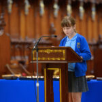 A child in blue reading from the pulpit in the cathedral.