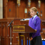 A child in purple reading from the pulpit in the cathedral.