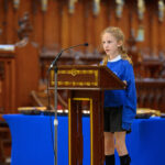 A child in blue reading from the pulpit in the cathedral.