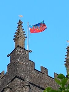 The top of the church tower with the conservation flag, red at the bottom and blue at the top, and a pale blue sky.