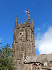 The church tower against a blue sky with a flag flying at the top of it.