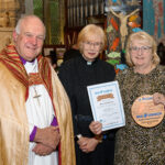 The Bishop of Truro to the left with with two others - one holding a certificate, one holding a plaque.