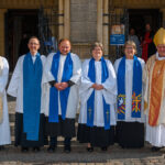 Six people lined up outside the cathedral for a photograph.