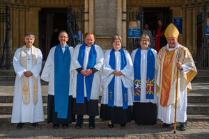 Six people lined up outside the cathedral for a photograph.