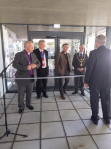 Bishops and dignitary in an entrance of the building ready to cut the ribbon in front of them.
