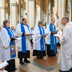 Four people in blue and whit in the cathedral with Bishop Hugh