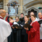 A group of people in black and red singing in the community.