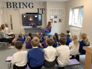 Children looking at a TV screen on the wall.