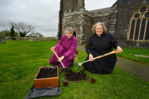 The bishop and another knelt by the tree and a wooden box.