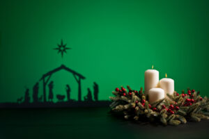 Silhouette of the nativity and an advent wreath in the foreground.
