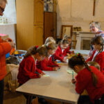 Children round a table doing crafts. There are also two adults.