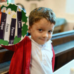 A child holding their advent craft in the pews of a church.