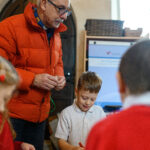An adult watching children doing Advent crafts.