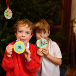 Two children with their crafts - a Christmas tree behind them.