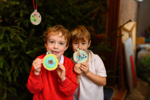 Two children with their crafts - a Christmas tree behind them.