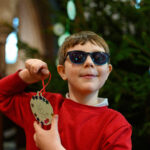 A child in front of a tree with their christmas craft