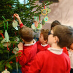 Children hanging their crafts on a Christmas tree