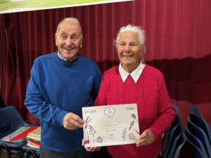 Two people holding a certificate - the background is red.