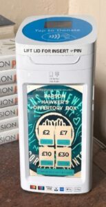 Shows the payment devise with a stack of white books behind it.