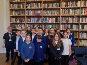 Children with a large bookshelf behind them.