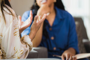 Hands gesture while talking with person wearing a blue shirt.