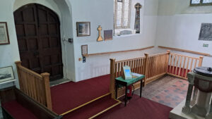 Image shows the inside of a church with the new ramp - red carpet and white walls.