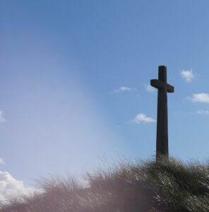 A cross on a hill with blue sky behind
