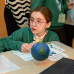 A child looking up with a model globe in front of them.