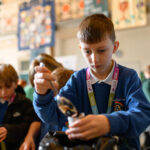 A child concentrating on a task using a spoon.