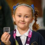 A child holding a glass display box with an insect in it.