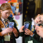 Children looking at the bean they have planted in their cups.
