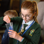 A child planting in a cup with blue paper.