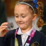 A child holding a glass display box with an insect in it.