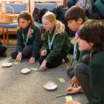 Children sat in a row with sticky notes and shells in front of them.
