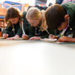 Children on the floor writing.
