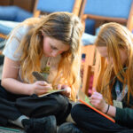Children on the floor writing.