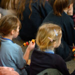 Children eating fruit kebabs.