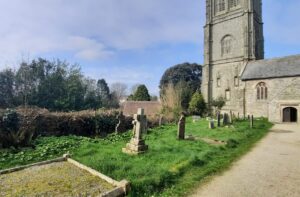 A church, churchyard and dead hedge.